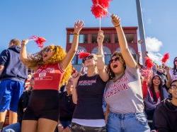 Students excited cheering at a football game on a sunny day